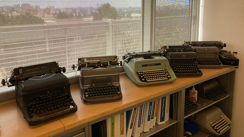A row of typewriters in front of an office window