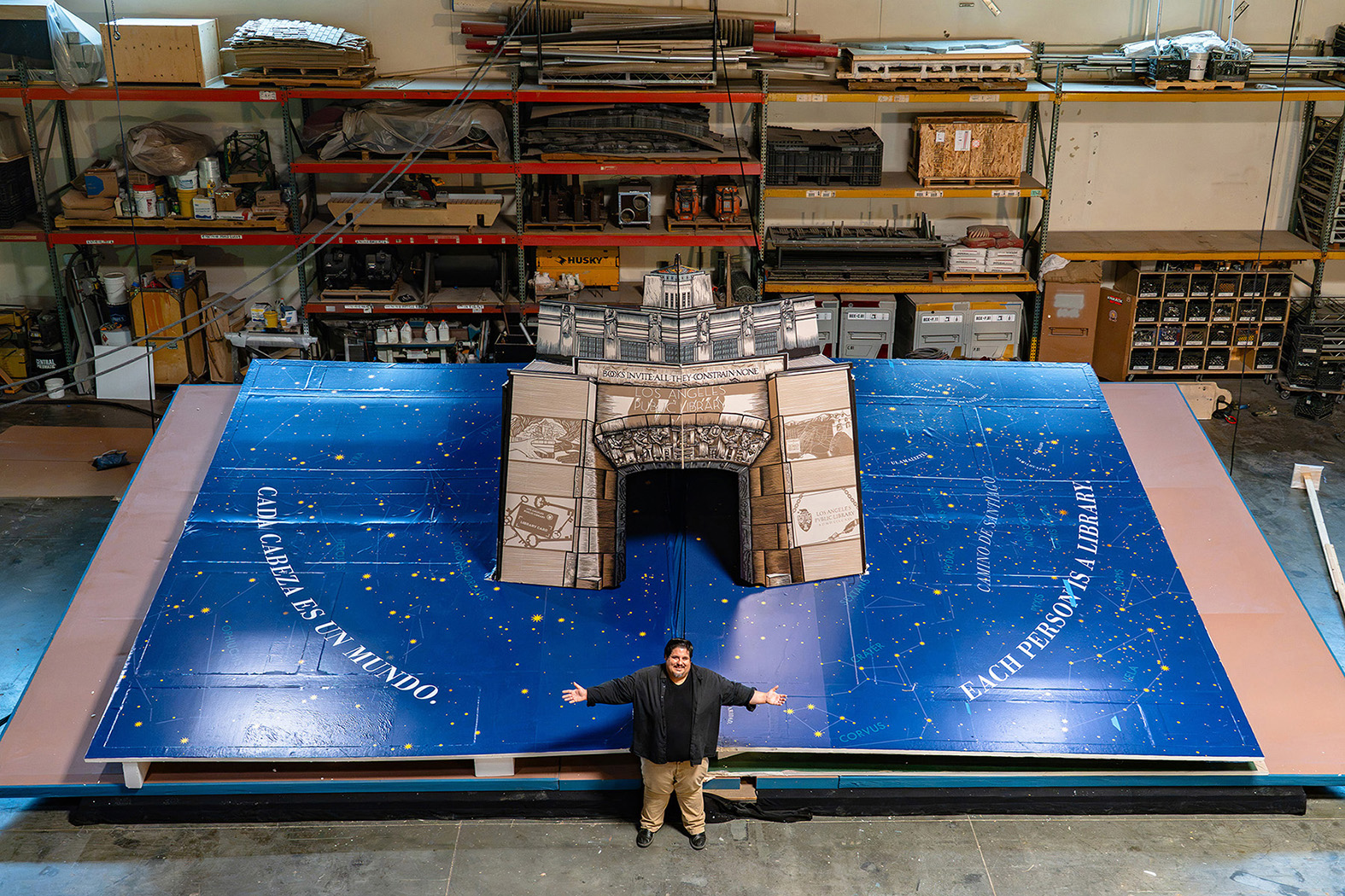 A large pop-up book installation featuring the Los Angeles Central Library, with a person standing in front of it for scale.